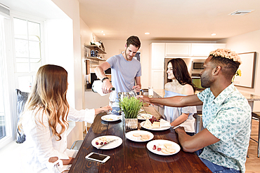 Man pouring champagne for friends at table