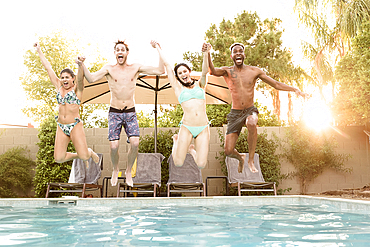 Friends holding hands jumping into swimming pool