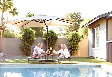 Caucasian couple toasting near swimming pool