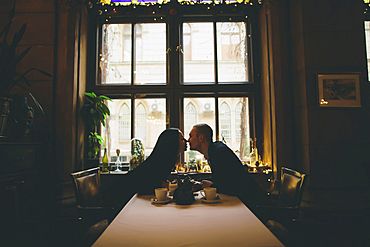 Caucasian couple sitting at table rubbing noses