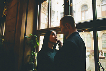 Caucasian couple embracing near window