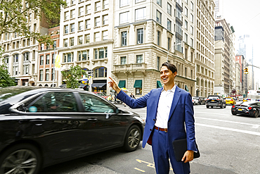 Caucasian businessman standing in street hailing taxi