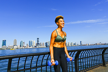 Mixed race woman lifting dumbbells at waterfront