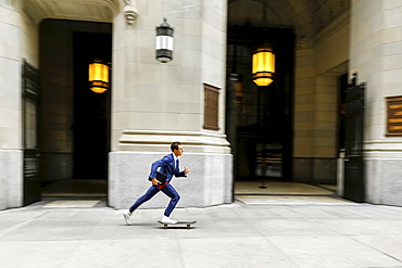 Caucasian businessman skateboarding on urban sidewalk