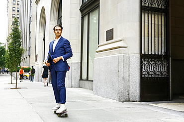 Caucasian businessman skateboarding on urban sidewalk