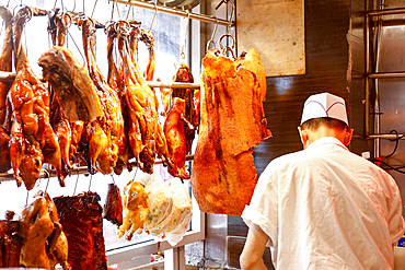 Butcher standing near hanging meat