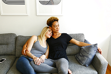 Women cuddling on sofa