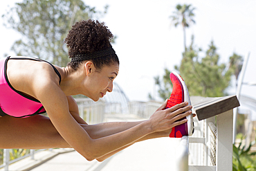 Mixed Race woman stretching leg on banister