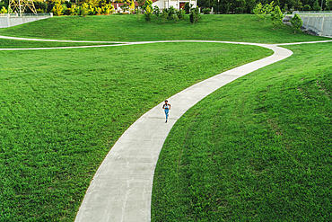 Distant mixed race woman running on winding path in park