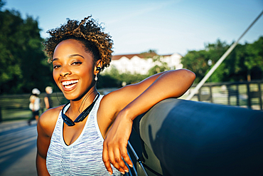 Smiling mixed race woman listening to earbuds on bridge