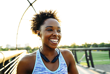 Mixed Race woman listening to earbuds on bridge and laughing