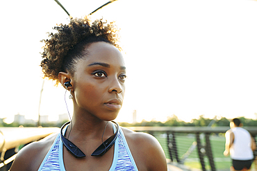 Mixed Race woman listening to earbuds on bridge