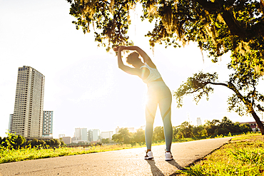 Mixed Race woman stretching on running path in park