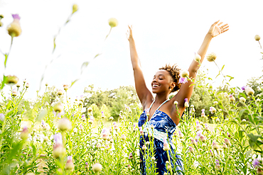 Smiling mixed race woman celebrating in field of wildflowers