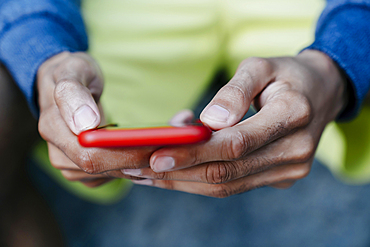 Hands of Black man texting on cell phone