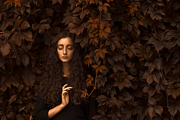 Serious Caucasian woman standing in autumn leaves