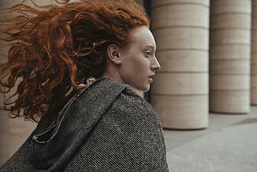 Wind blowing hair of Caucasian woman near pillars