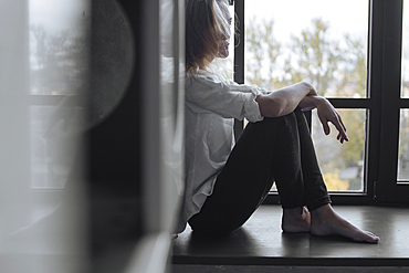 Caucasian woman sitting on the windowsill