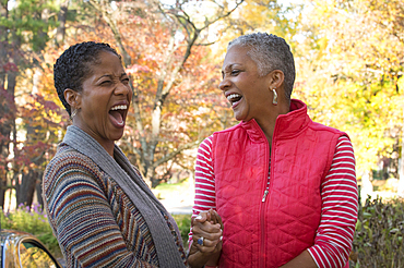 African American women holding hands and laughing outdoors