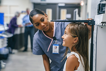 Nurse measuring height of girl in hospital