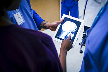 Doctors examining x-ray of skull and jaw on digital tablet