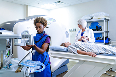 Technician preparing scanner for doctor comforting patient