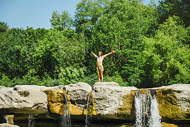 Caucasian man standing on rocks near waterfalls