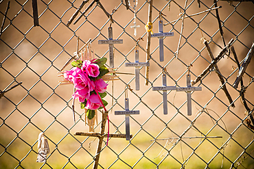 Crucifixes and flowers hanging on memorial fence