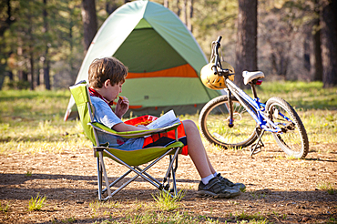 Caucasian boy reading book at campground