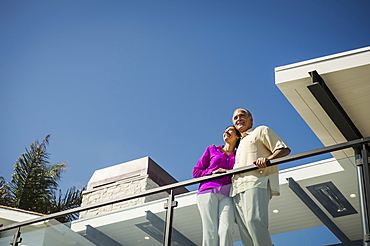 Smiling couple standing on modern balcony