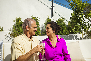 Older couple toasting on modern backyard patio