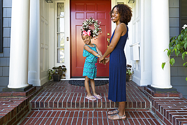 Portrait of smiling mixed race mother and daughter on front stoop