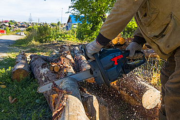 Caucasian man cutting logs with chainsaw