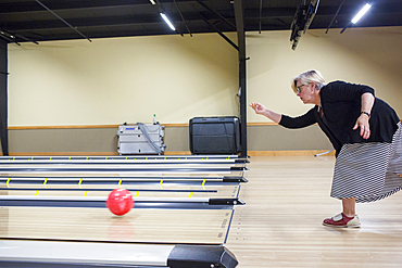 Caucasian woman releasing bowling ball in lane