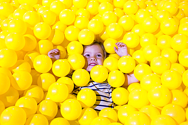 Caucasian girl laying in pile of yellow balls