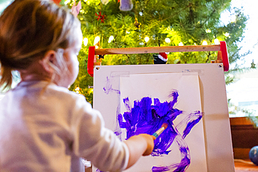 Caucasian girl painting with purple paint on paper