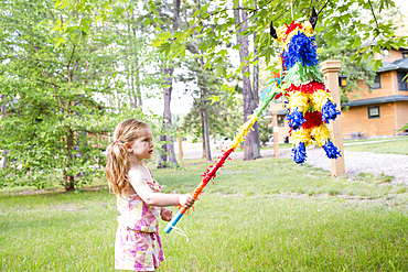 Caucasian girl hitting pinata outdoors