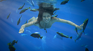 Asian woman swimming underwater with fish