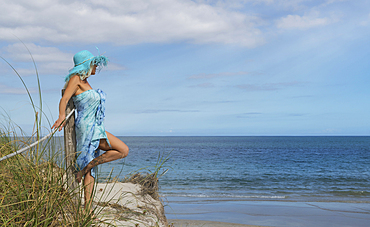 Caucasian woman leaning on wooden post at beach