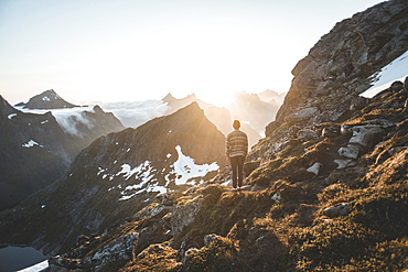 Caucasian man sitting on rock admiring scenic view of mountain lake