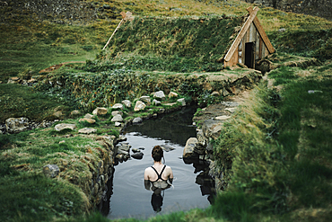 Caucasian woman swimming in pond near rural house