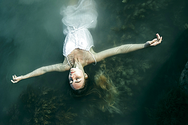 Caucasian woman wearing dress floating in water