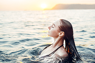 Caucasian woman swimming at sunset