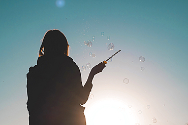 Silhouette of a woman waving bubble wand