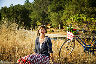 Laughing Caucasian woman sitting near bicycle