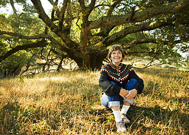 Smiling Caucasian woman sitting near tree