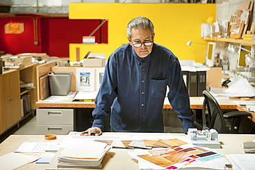 Serious Hispanic designer examining color swatches in office