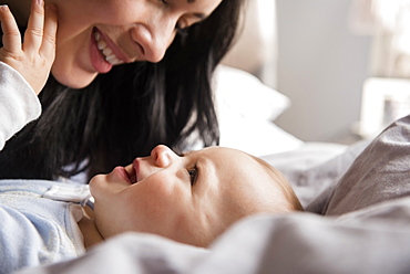 Close up of Caucasian mother laying on bed with baby son