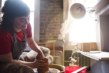 Caucasian woman shaping pottery clay on wheel