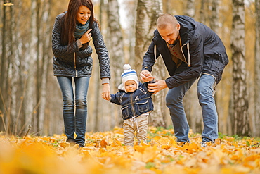 Middle Eastern parents walking with baby son in autumn